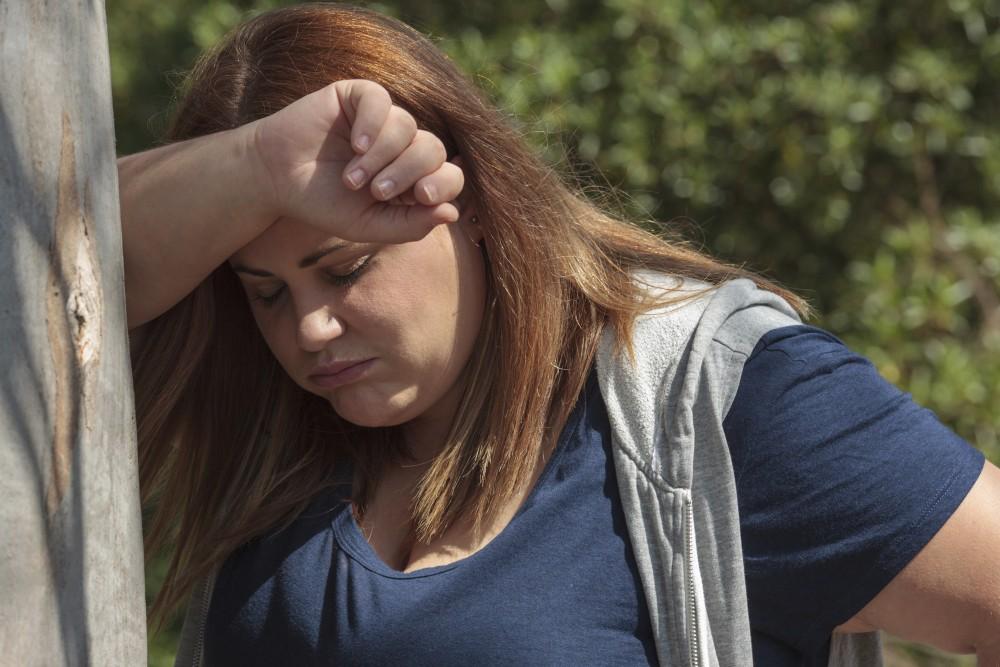 Overweight woman resting leaned against a tree