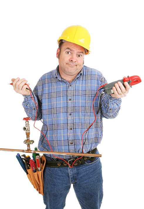 Electrician confused by a plumbing project.  Hes holding a voltage meter which is useless on a plumbing pipe.  Isolated on white.