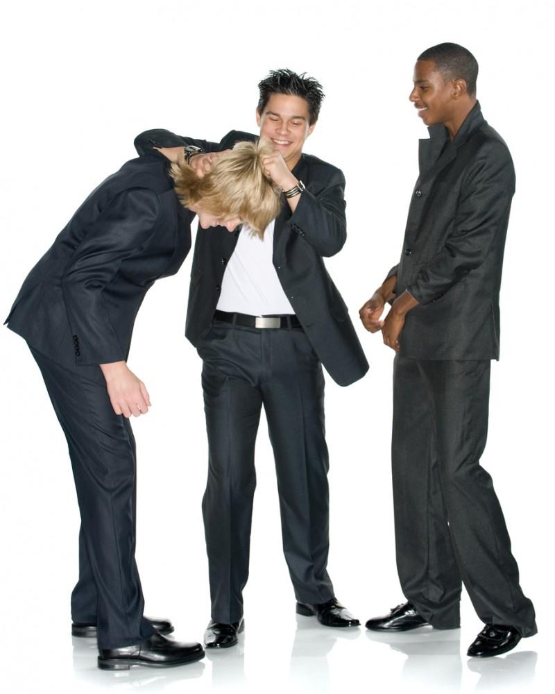 "Fun, light, and lively image of three young business men. Asian American man is giving a noogie to the new guy. Studio shot. Isolated on white."