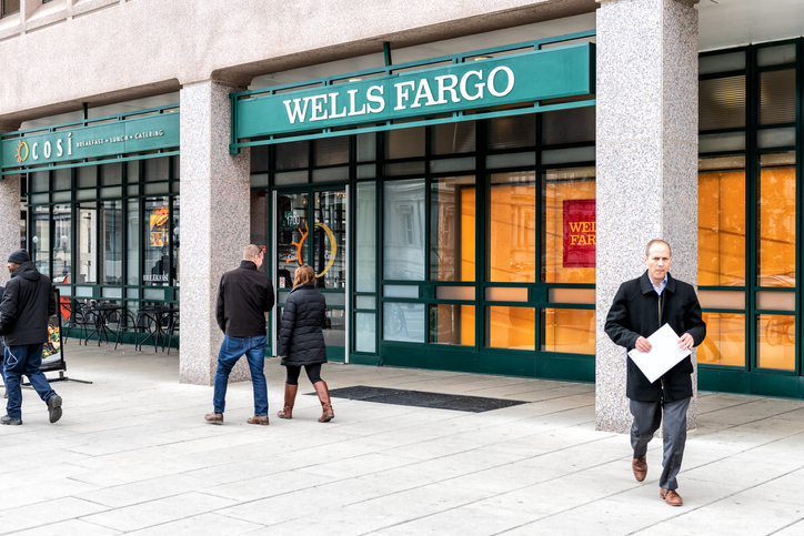 Washington DC, USA - March 9, 2018: Wells Fargo bank branch entrance, facade, building, windows, many people walking on sidewalk street in capital city, business, businessman holding document